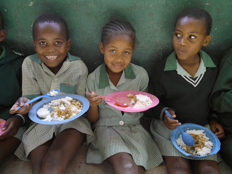 three young girls hold plates of food