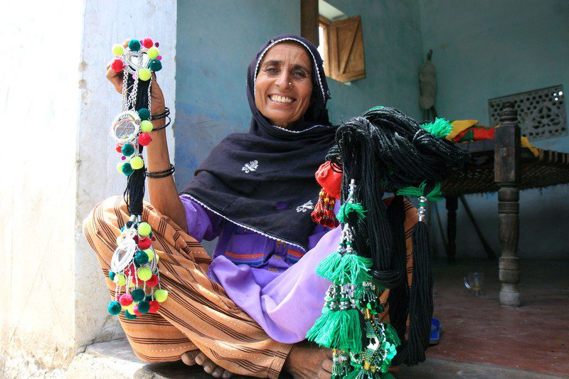 Asia, holding parandas (hair decorations) that she makes and sells. Photo: Jane Beesley/Oxfam