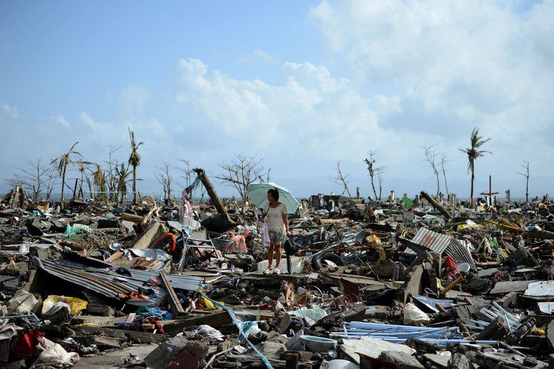 A survivor walks among the debris of houses destroyed by Super Typhoon Haiyan in Tacloban in the eastern Philippine island of Leyte on November 11, 2013.