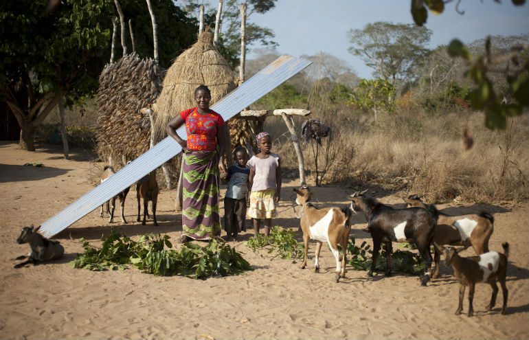 Goats from Oxfam Unwrapped helped build the new house that Delfinia stands in front of with her two children