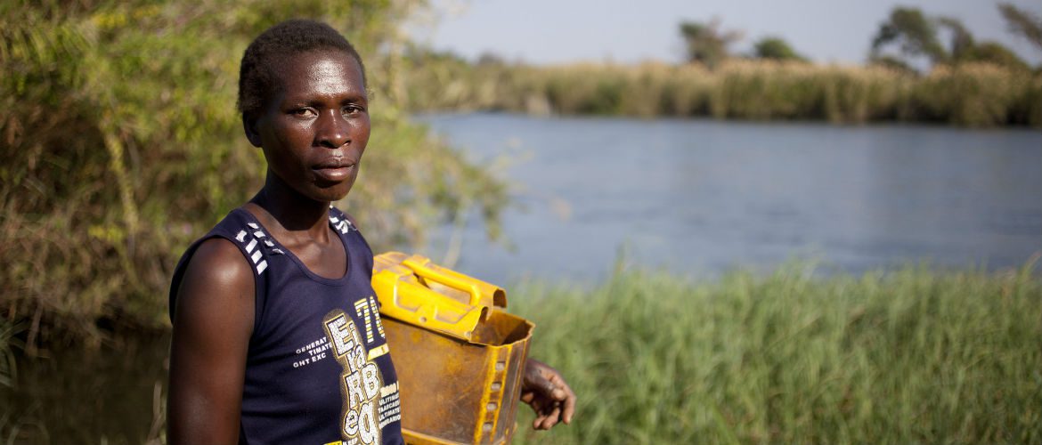 Barbara stands by the river to collect clean water. If everyone paid their fair share of tax, we could have a chance to meet the basic needs of people living in poverty, give them control over their own lives and the opportunity to change their futures.