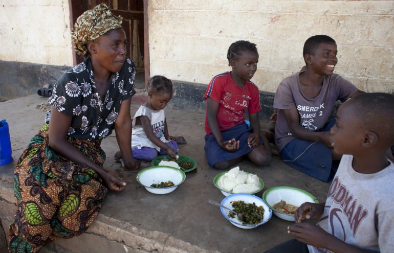 Irene and her children enjoy a meal together outside their home in Zambia, Africa.