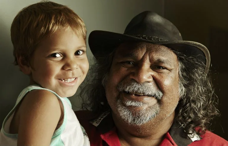 Photo: Jason Malouin/OxfamAUS A young Aboriginal child and an older Aboriginal man pose together to highlight the need to Close the Gap for the next generation