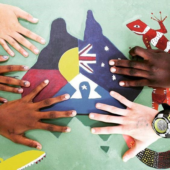 Indigenous and non-Indigenous hands rest on a map of Australia comprising the Australian, Aborginal and Torres Strait Islander flags.