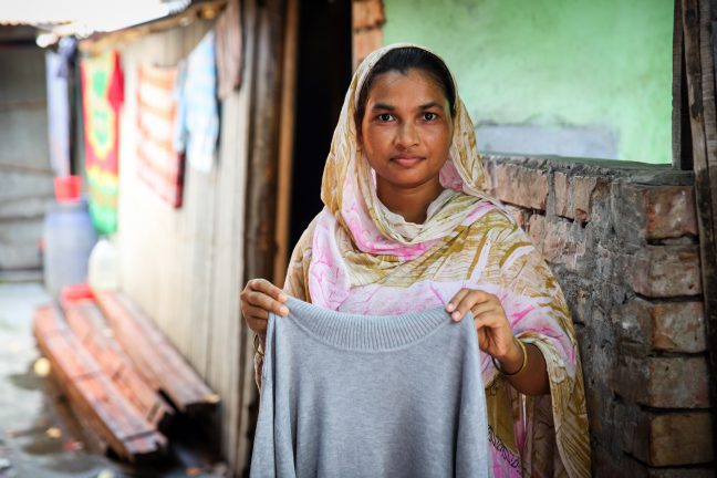 Textile operator Anju (22) is showing how she works in the factory. Mirpur, Dhaka, Bangladesh