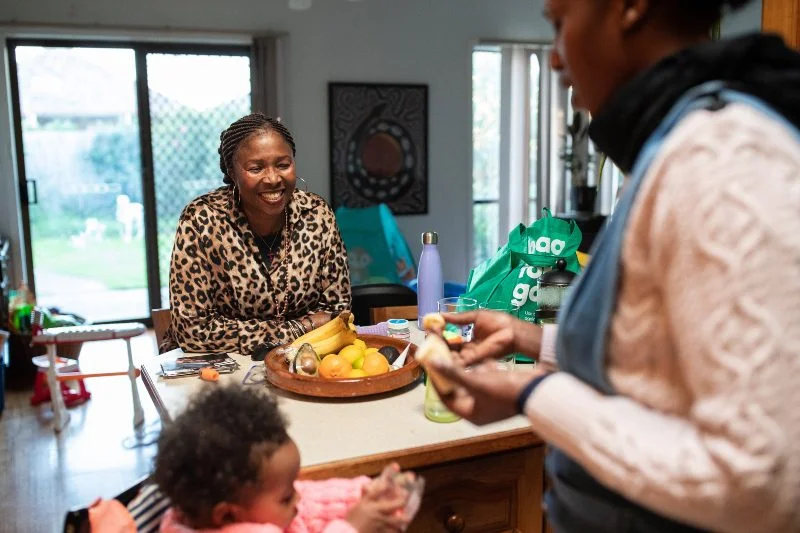 Photo: Kim Landy/Oxfam Australia A family sits around a table in a kitchen.