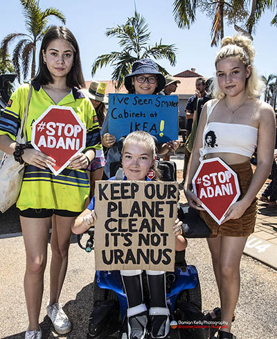 Students holding "Stop Adani" signs and a #ClimateStrike placard that reads "Keep our planet clean: it's not Uranus"