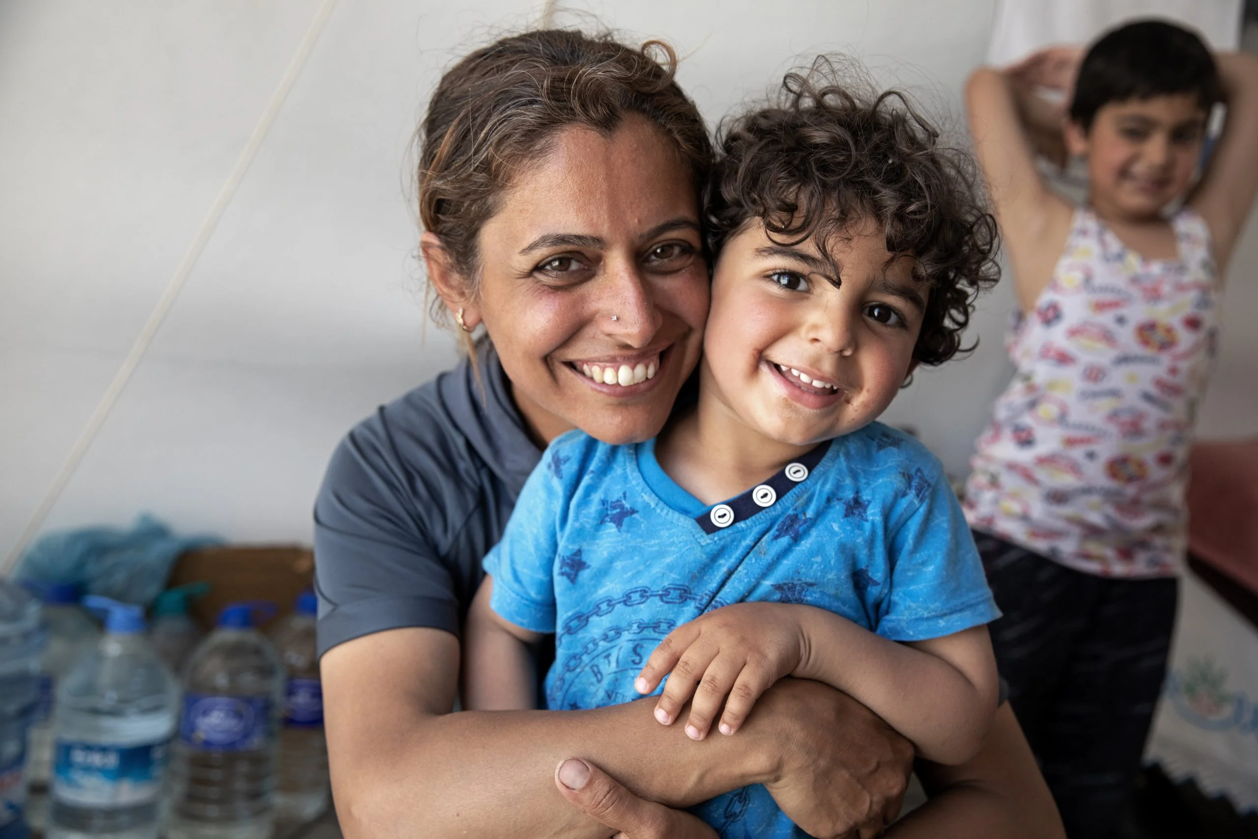 Turkiye: Mother and her two children are sitting in their tent. Photo: Delizia Flaccavento/Oxfam. Turkiye: Mother and her two children are sitting in their tent. Photo: Delizia Flaccavento/Oxfam.