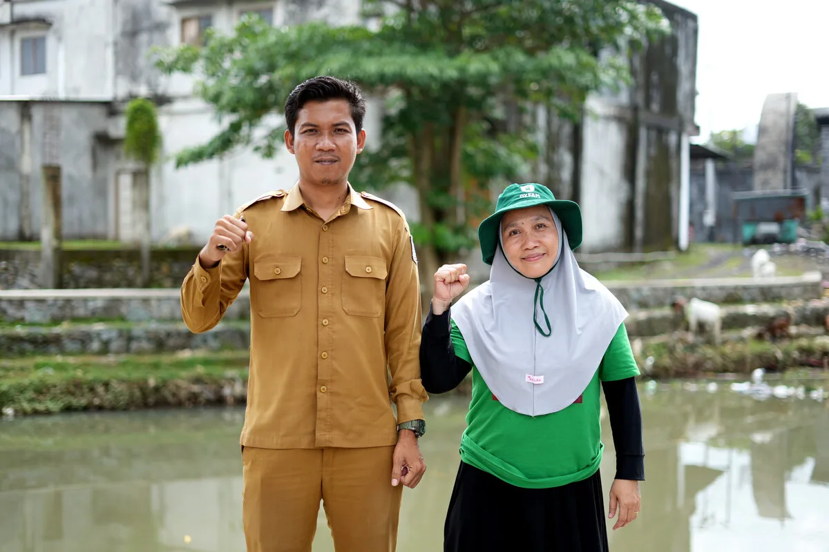 Lombok, Indonesia: Mariani and Satria support their community in anticipatory action. Mariani measures and documents water levels using an obrometer and Satria is the village secretary and chief of the Village Disaster Preparedness Team (TSBD). Photo: Aimee Han/Oxfam